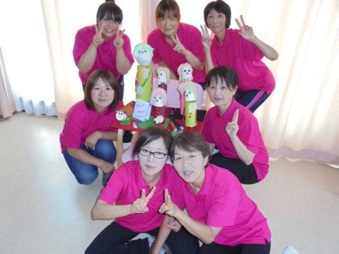 自分たちが作成した作品の周りで、おそろいの服を着たスタッフ