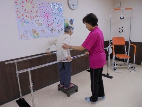 スタッフの補助を受けながら、昇降運動をしているご入居者様