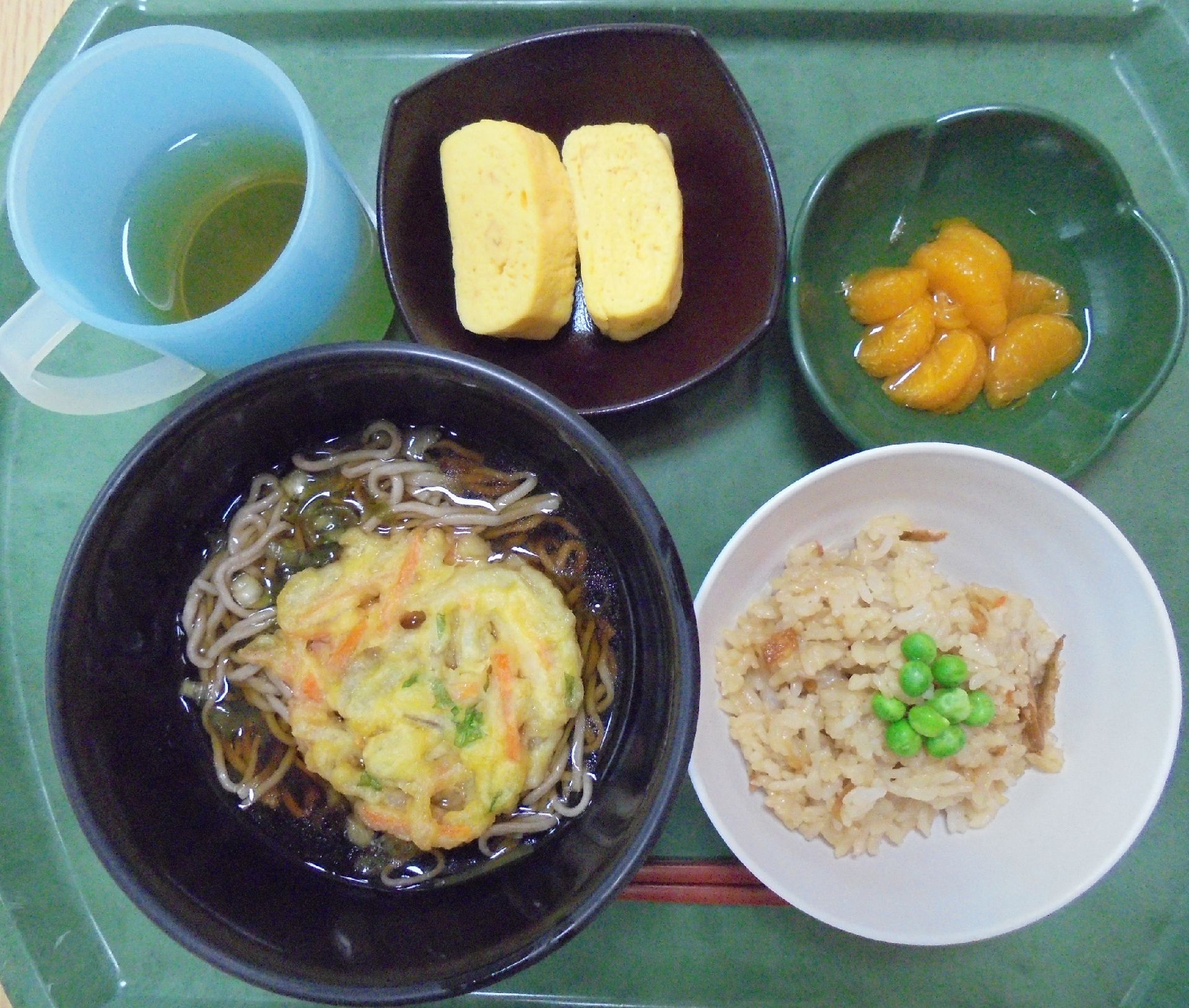 たまご焼きやみかんのデザートが付いた、炊き込みご飯とかき揚げそばのセット