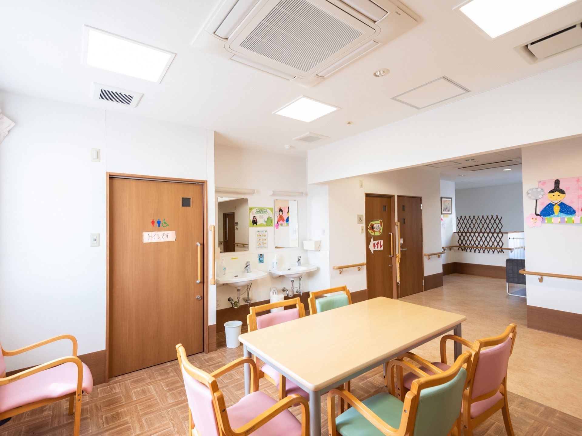 テーブルと椅子の置かれた共有スペース。スペースのすぐ近くにはトイレと洗面所も備え付けられているのが見える。