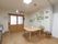 木目調のフローリングの部屋にテーブルがあり、椅子と丸椅子が置かれている。壁に写真などが掲示されている。右側にロッカーが見える。