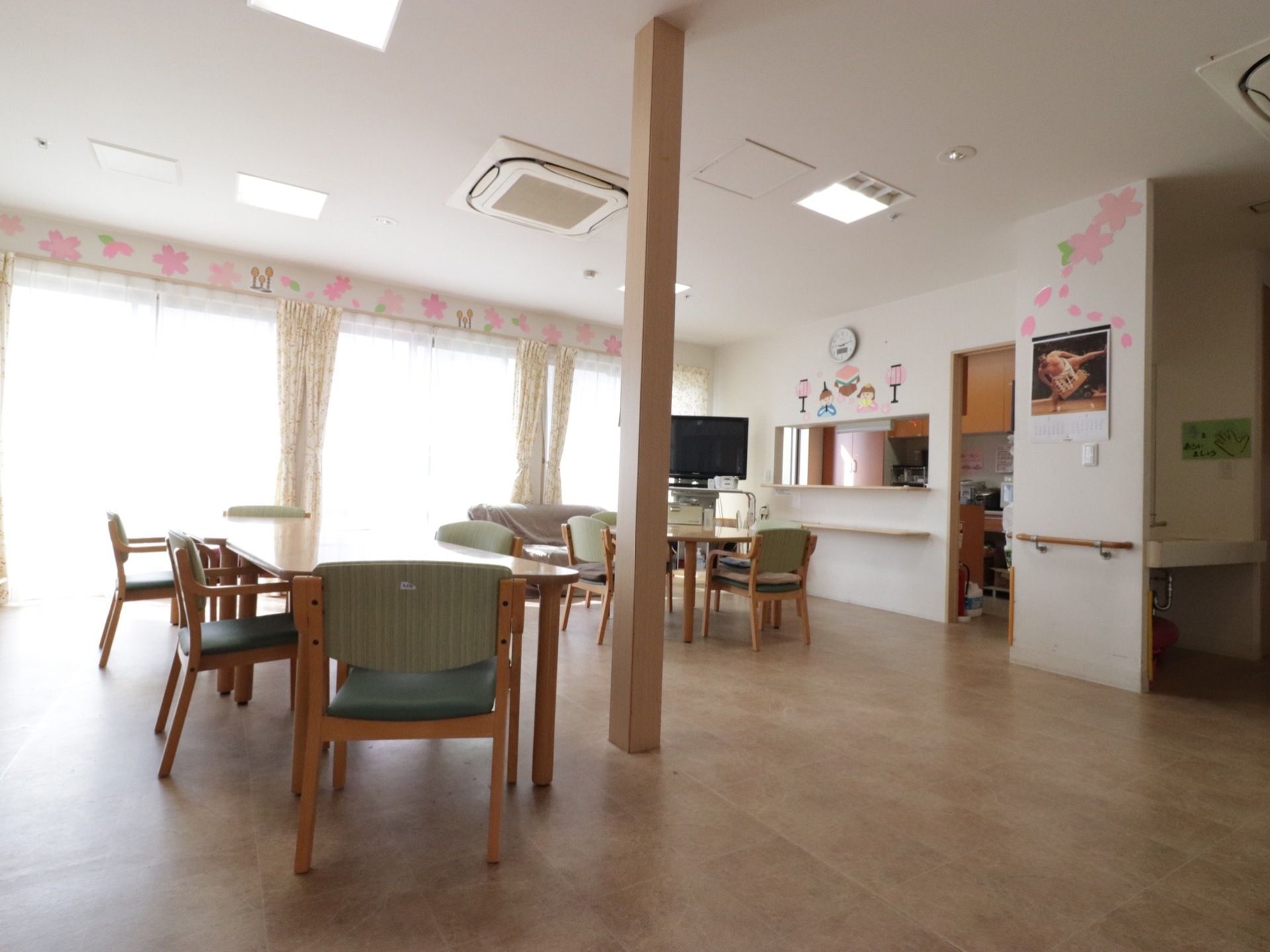 窓から明るい自然光が差し込む広々とした食堂である。対面式キッチンが併設されている。椅子がセットされたダイニングテーブルが置かれている。