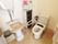 オストメイト用の便器も設置されているトイレである。壁に可動式の手すりが取り付けられている。チェストやゴミ箱が置かれている。