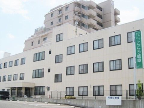 広い駐車場をもつ、3階建ての白い壁面をした施設の外観