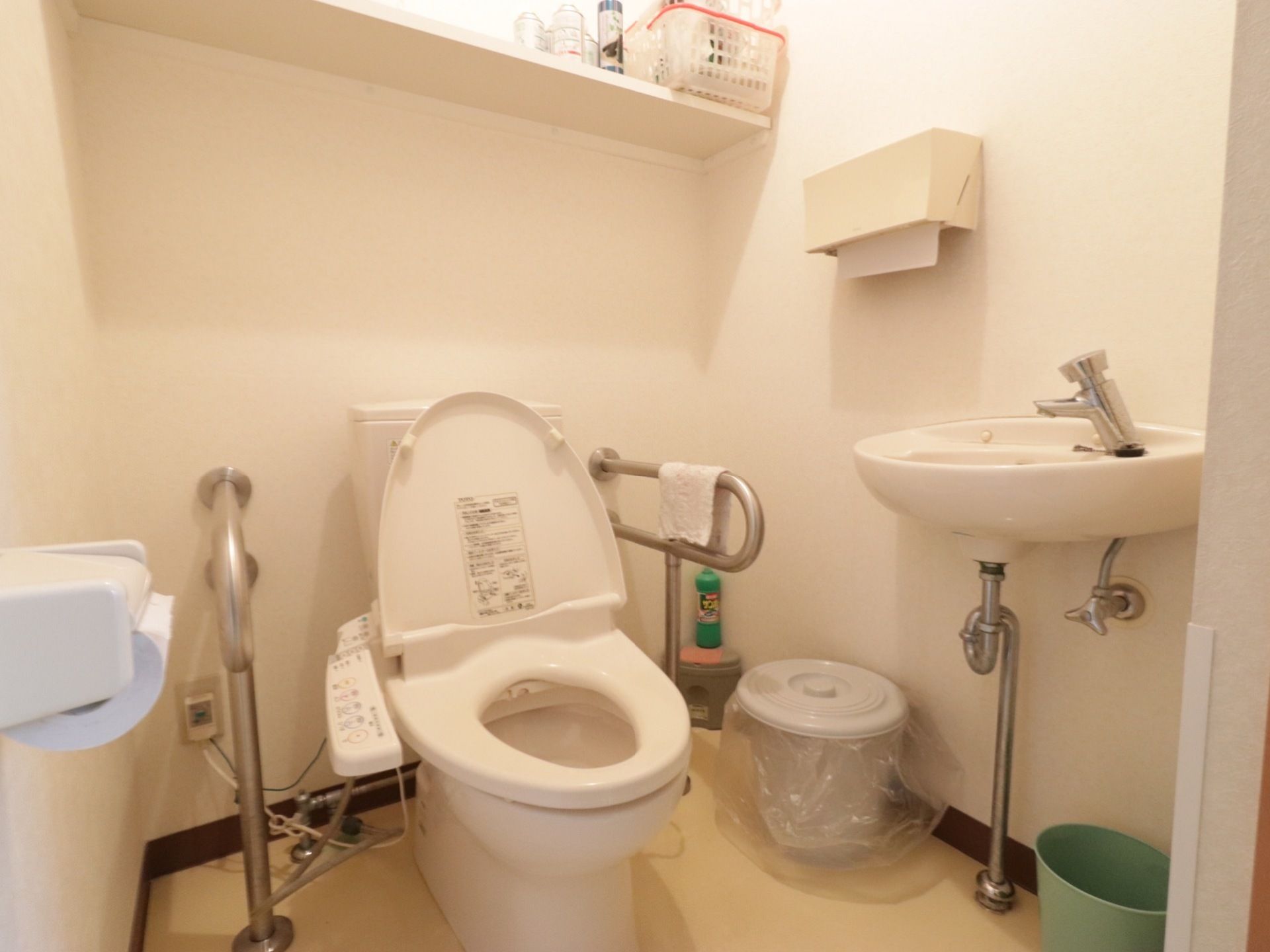トイレの洗面台では、蛇口の上部を手で押して水を出す仕組みだ。便座の横に肘掛け状のパイプが設置してある。