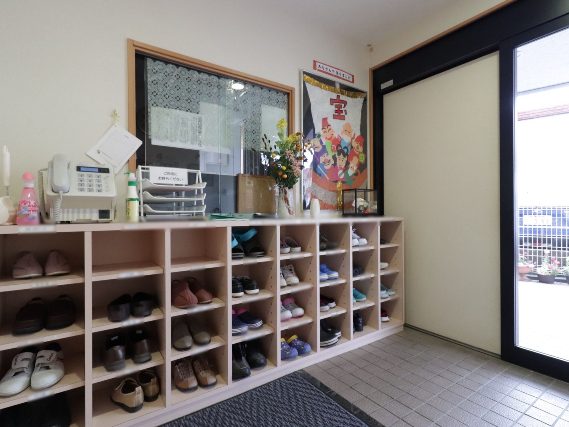 玄関を入って右側には窓口がある。その前に靴棚を置いており、上部をカウンター代わりに使い置物などで飾っている。