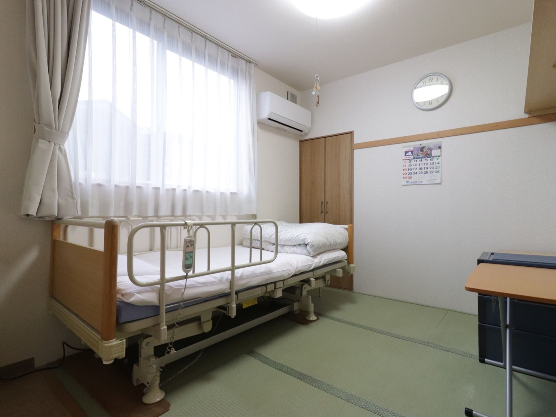 居室はドア前がフローリングで、その他の部分には畳が敷いてある。ベッドを置く際には、クッション材を足の部分に設置する工夫をしている。