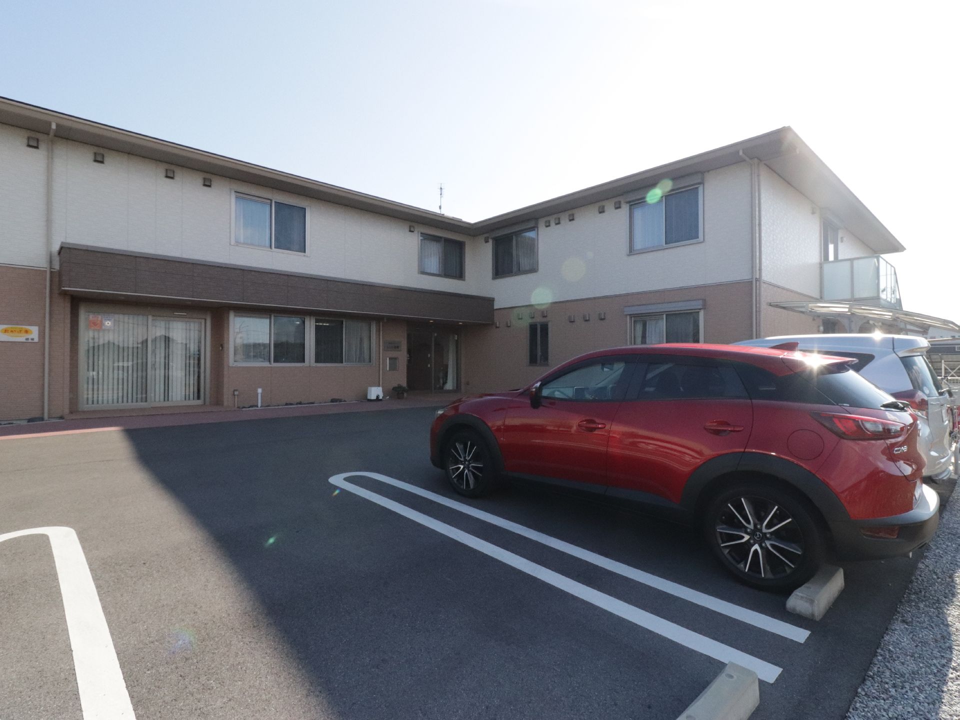 二階建て住宅型老人ホームで外観は落ち着いた雰囲気の色調である。駐車場を施設の入口前面に広くゆったりととられ移動がスムーズである。