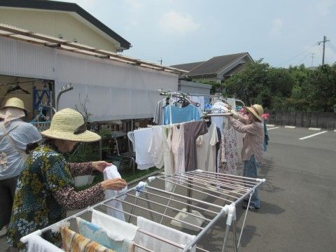天気のいい日に麦わら帽子をかぶって洗濯を干すスタッフ