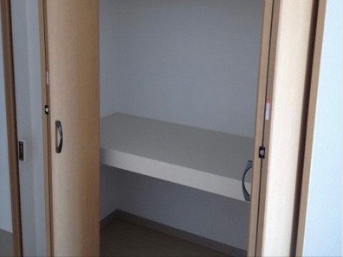 収納コーナー。折り戸式の扉は観音開きで、扉を開けても邪魔にならない。中央に棚があり、上下二段に仕切られている。