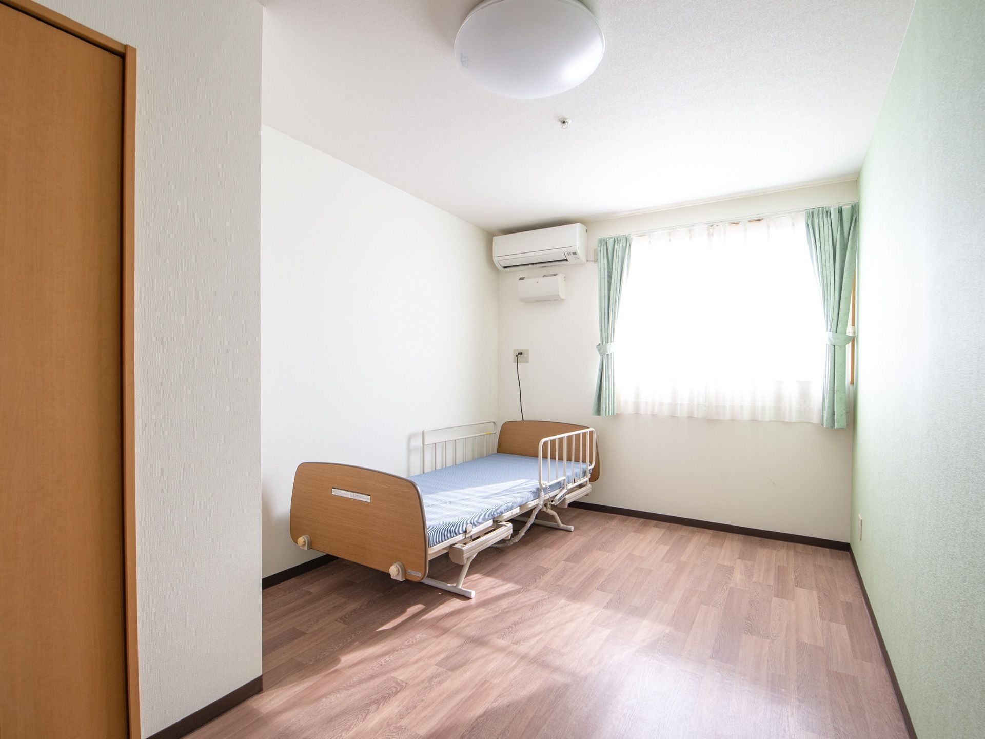 白で統一された壁に木目調の床で、明るく温もりのある居室になっている。備えつけのベッドには手すりがあるので、起き上がり動作がスムーズに行える。