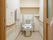 白色で統一された明るく綺麗なトイレである。備えつけの手すりは稼働式になっているので、安全に使用できる。ドアは木目調で温もりを与えてくれる。