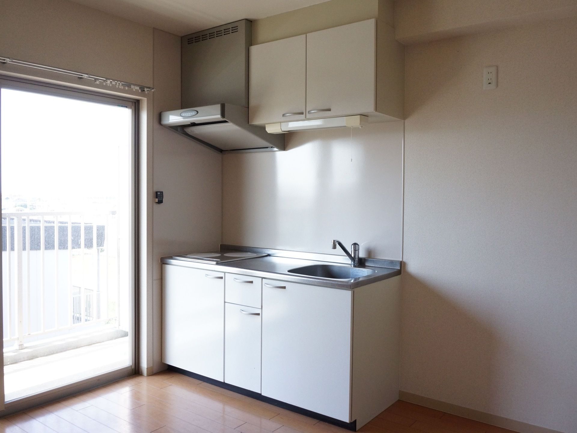 居室にはIHコンロが２つついており、作業スペースも確保されたミニキッチンが備え付けられている。窓が大きく、室内が明るい。