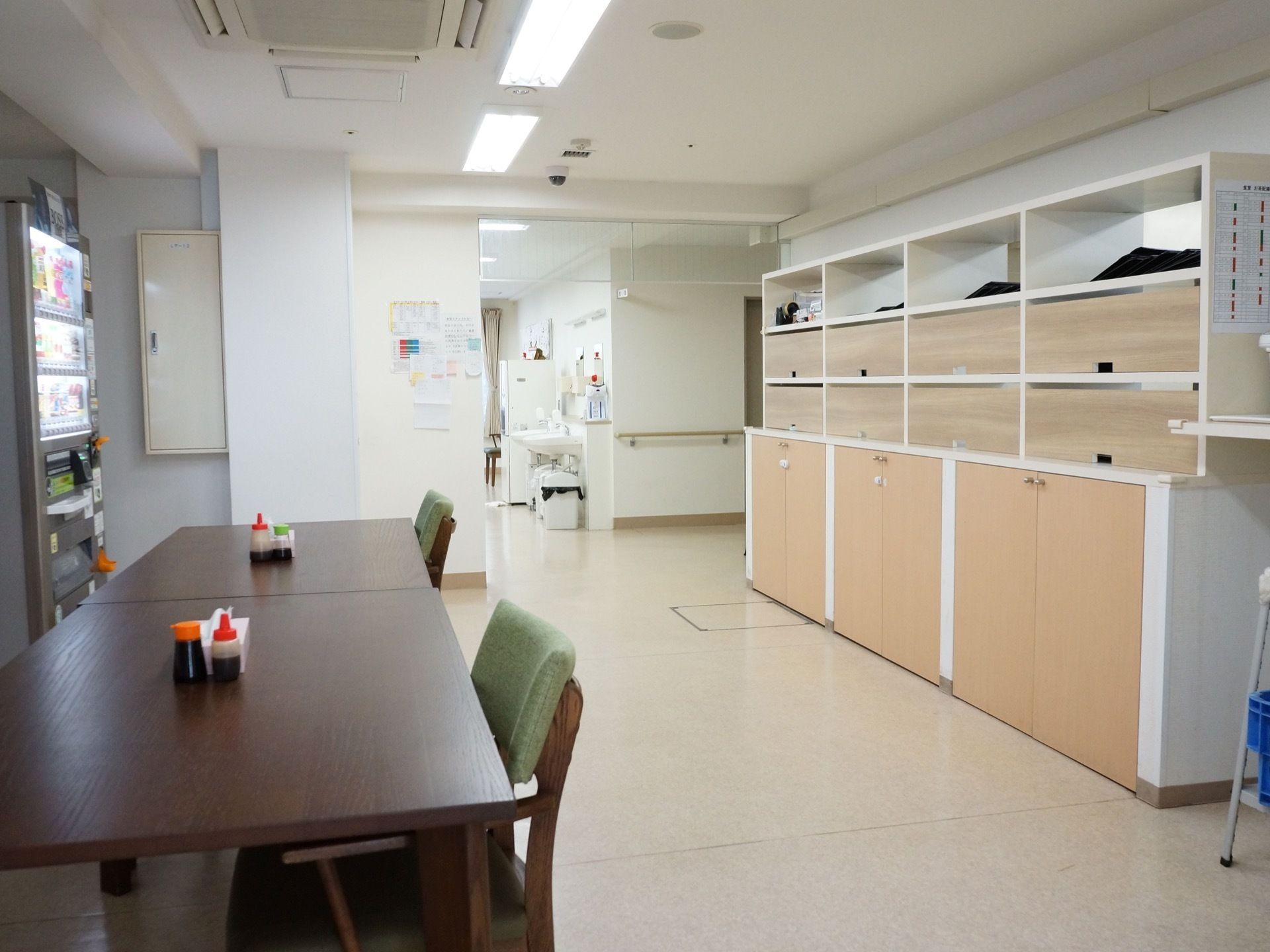 緑の椅子に濃いブラウンのテーブルが置かれている。テーブルの上には醤油などの調味料とティッシュが置かれている。