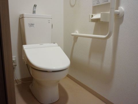 衛生的できれいなトイレである。便座脇には動作に不安のある入居者様のためにＬ字型の手すりを設置している。