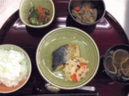 お盆にのせられた食事である。ご飯や主菜、副菜、汁物など種類が豊富である。箸とスプーンが添えられている。