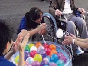 夏祭りでヨーヨー釣りを楽しむ、ご入居者様とスタッフ