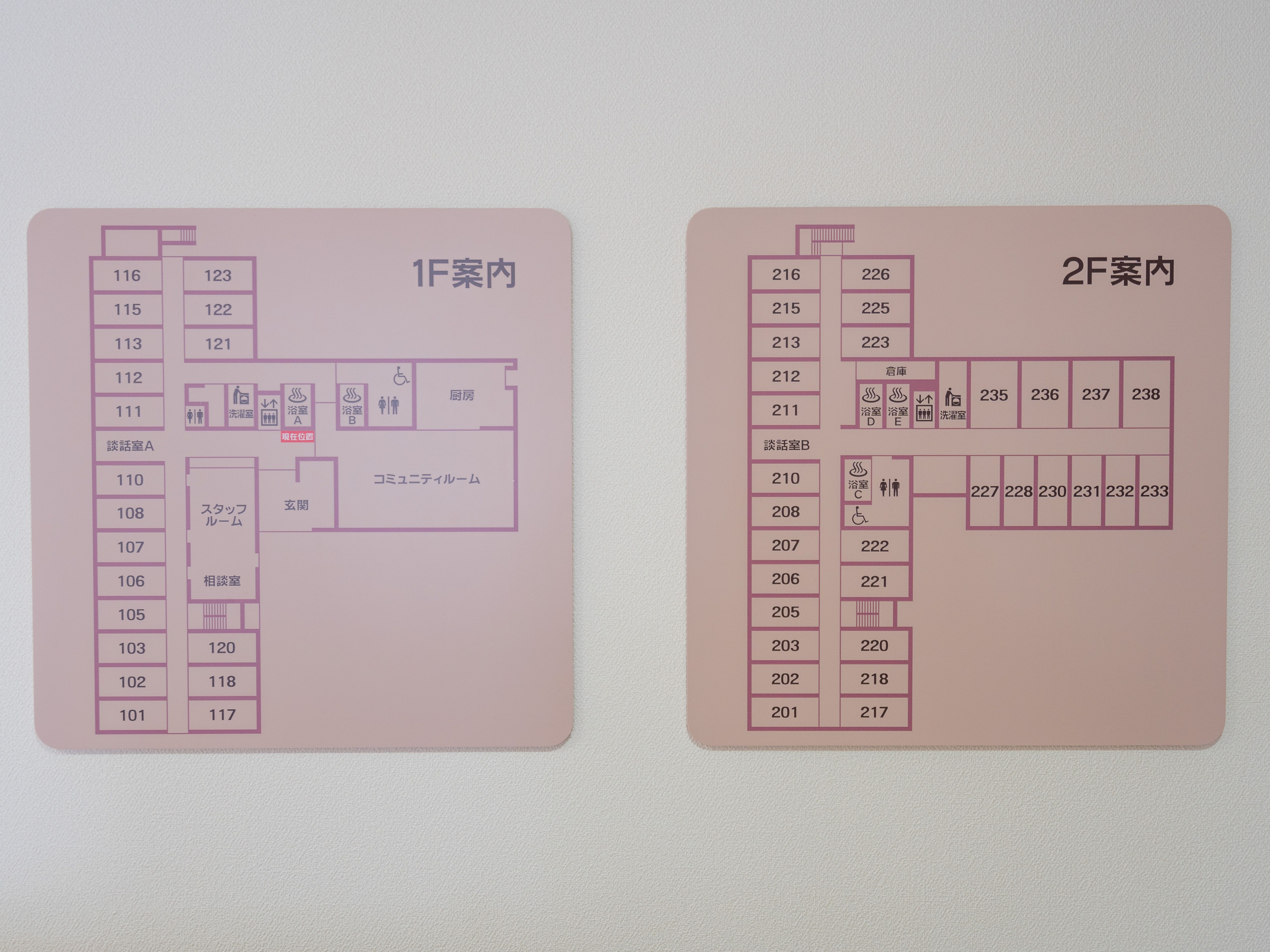 白い壁に取り付けられた１F案内、２F案内と書かれたピンク色のプレート