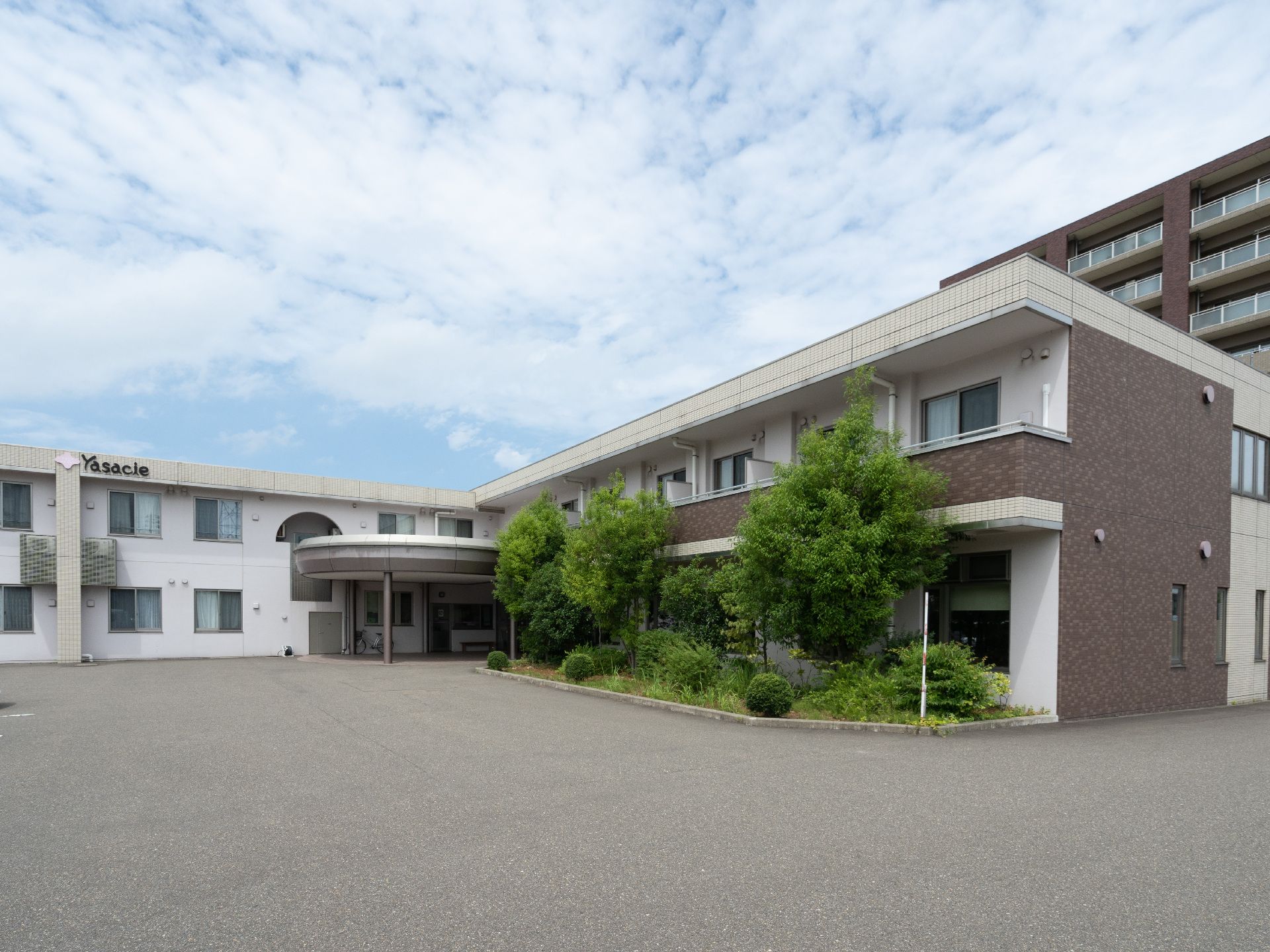 窓際に植物が植えられているL字で２階建ての建物