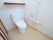 白い部屋に置かれたトイレとその横の壁に設置されたL字の手すり