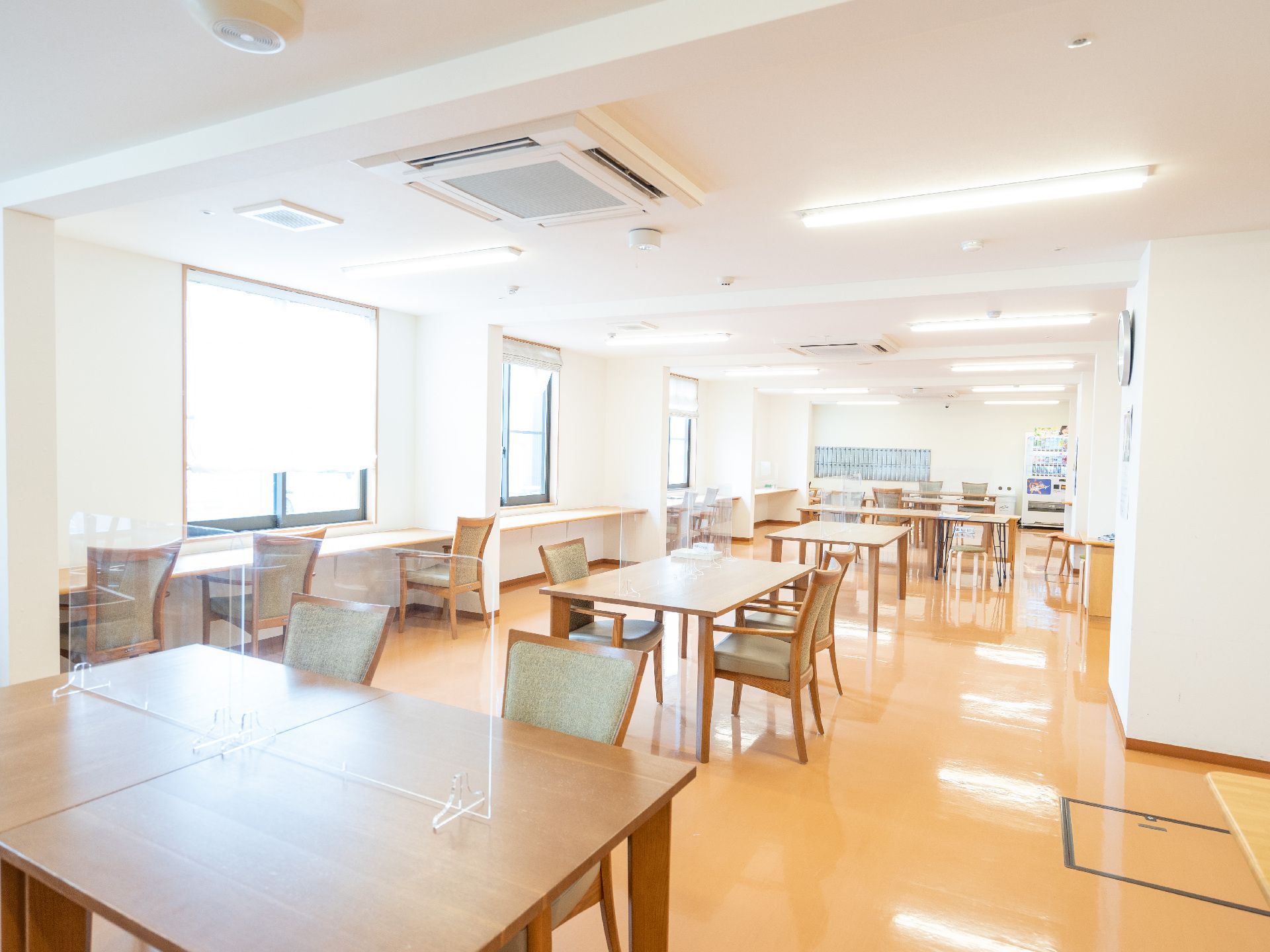 白い柱のある広間に並んだ仕切りのついた木製の机
