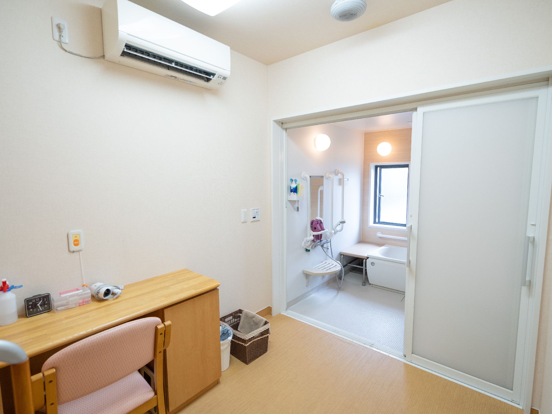 扉があいた浴室の手前にある机と椅子が壁際に置かれた部屋