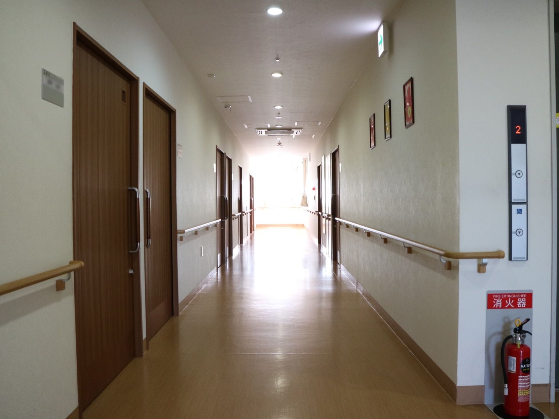 幅を広く取った真っ直ぐな廊下である。左右の壁には、手すりがかかっている。エレベーター横の壁際に消火器が置かれている。