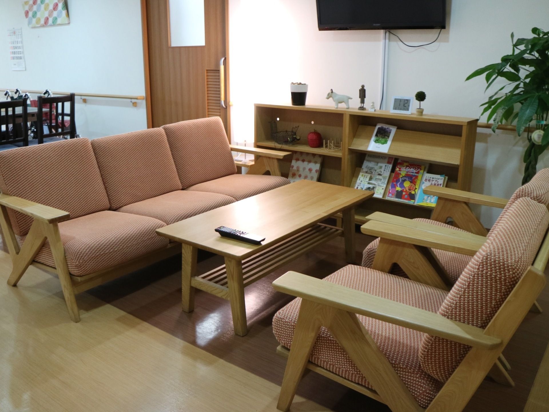 ローテーブルや３人掛用と１人用ソファチェア用意された談話スペースである。壁にテレビがある。