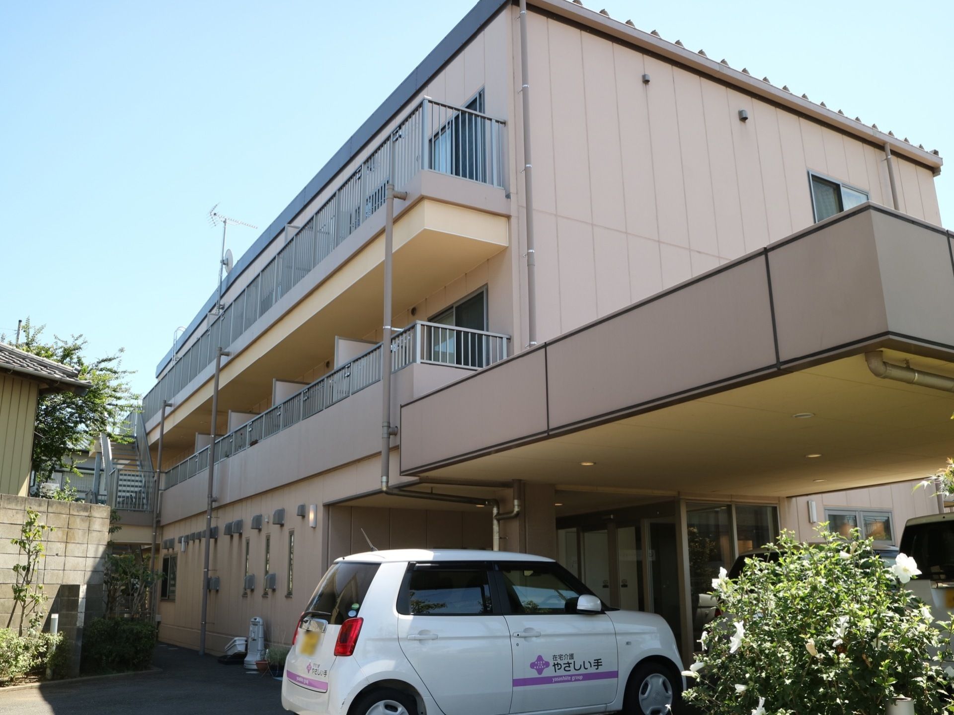 施設はベージュ色の３階建ての建物である。居住階には、ベランダが付いている。車寄せがエントランスに設けられている。