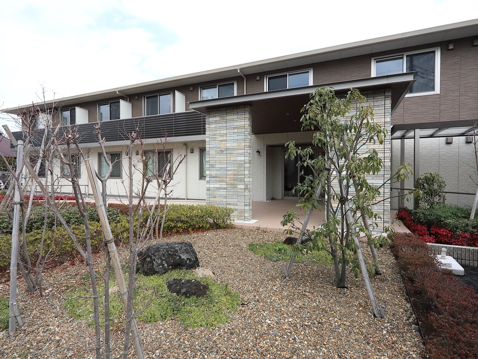 ホームの建物から張り出した屋根がある。入口は少し奥まっており、天候の影響を受けにくい。庭にタイルの通路が設置されている。