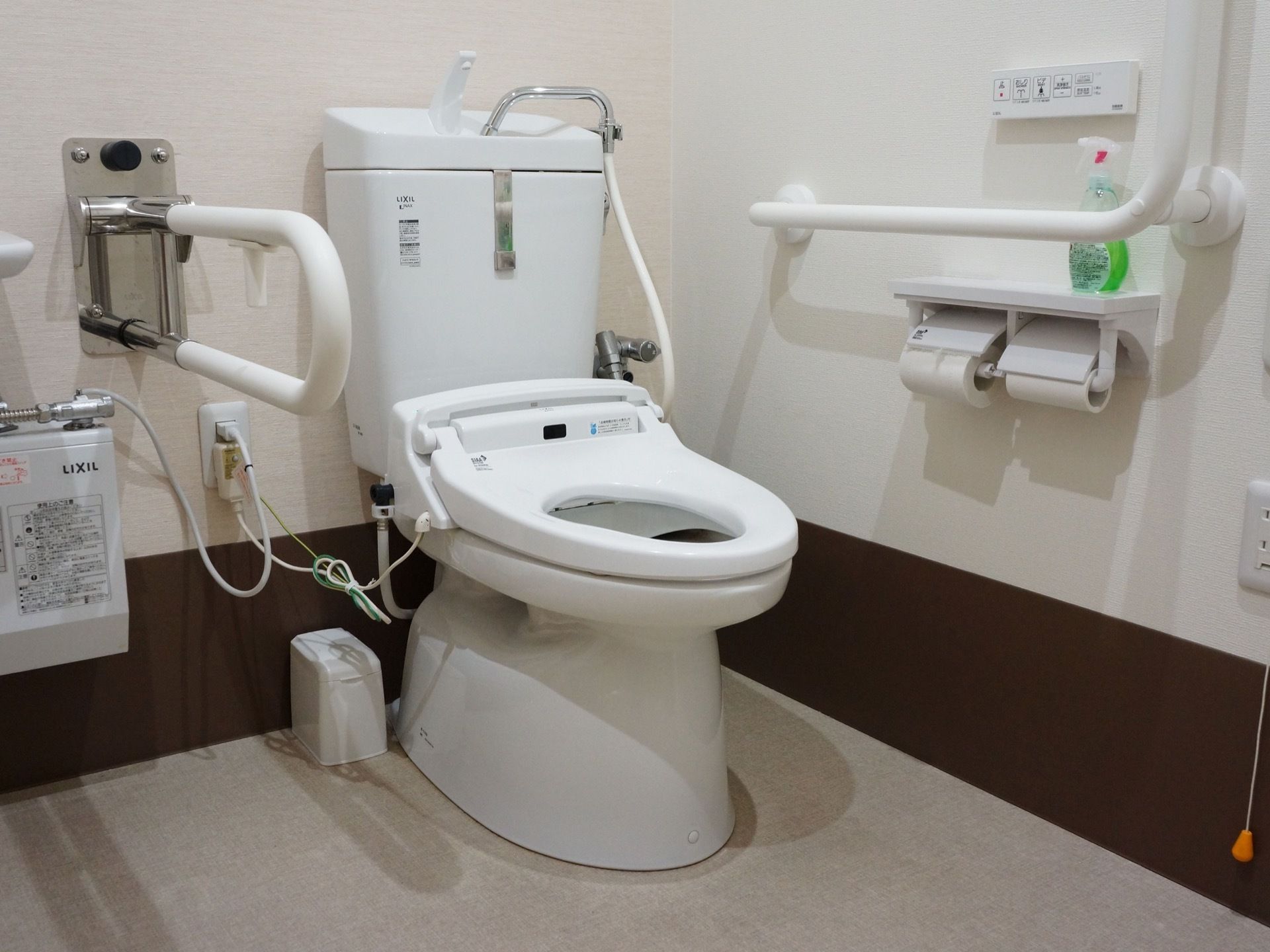 温水洗浄便座器が完備されたトイレは、L字型、レバー式手すり、トイレットペーパーホルダーが設置されている。
