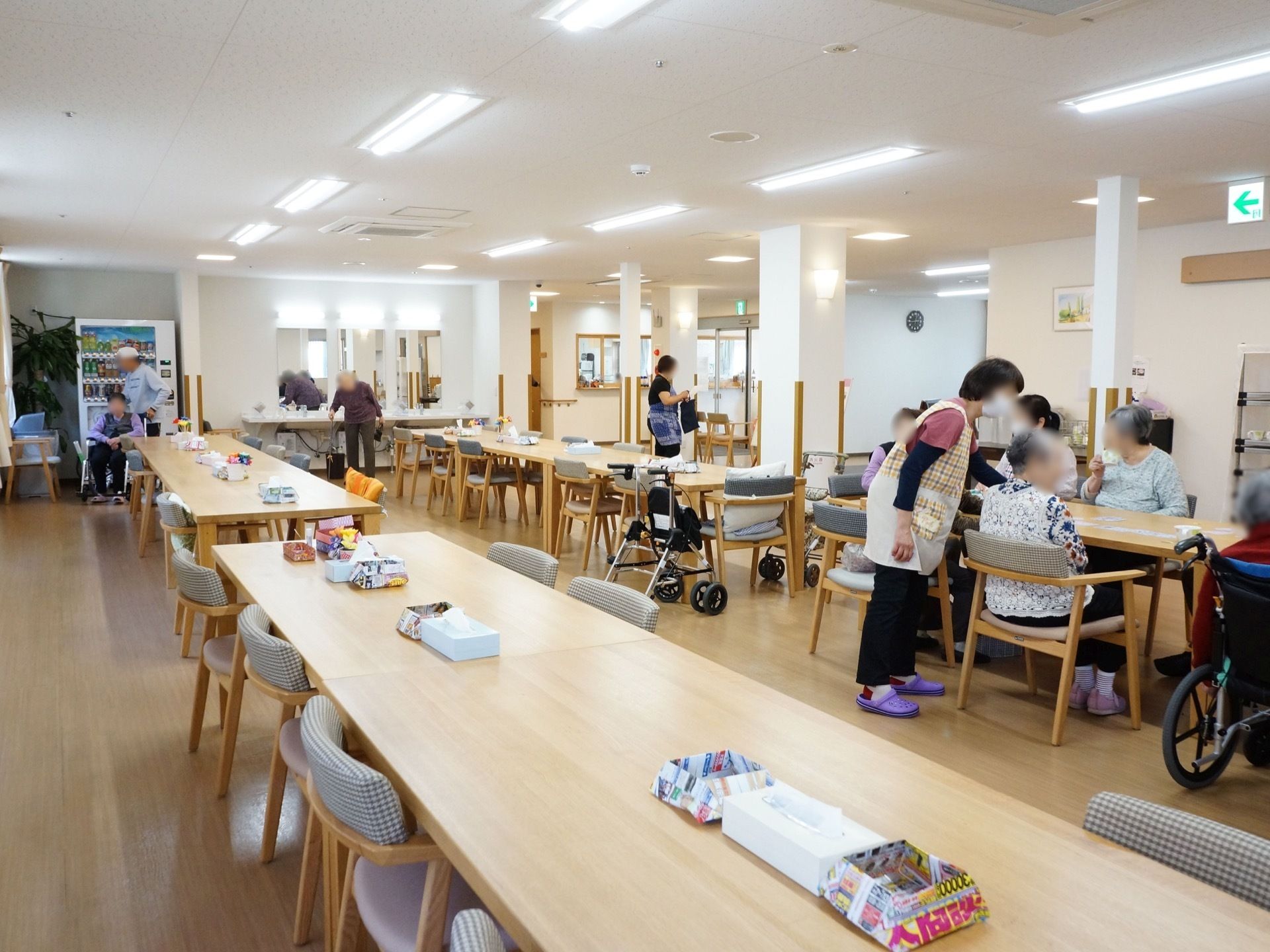 食堂スペースである。テーブルセットが間隔を置いて2列に並べられている。奥には洗面台と自動販売機を備えている。