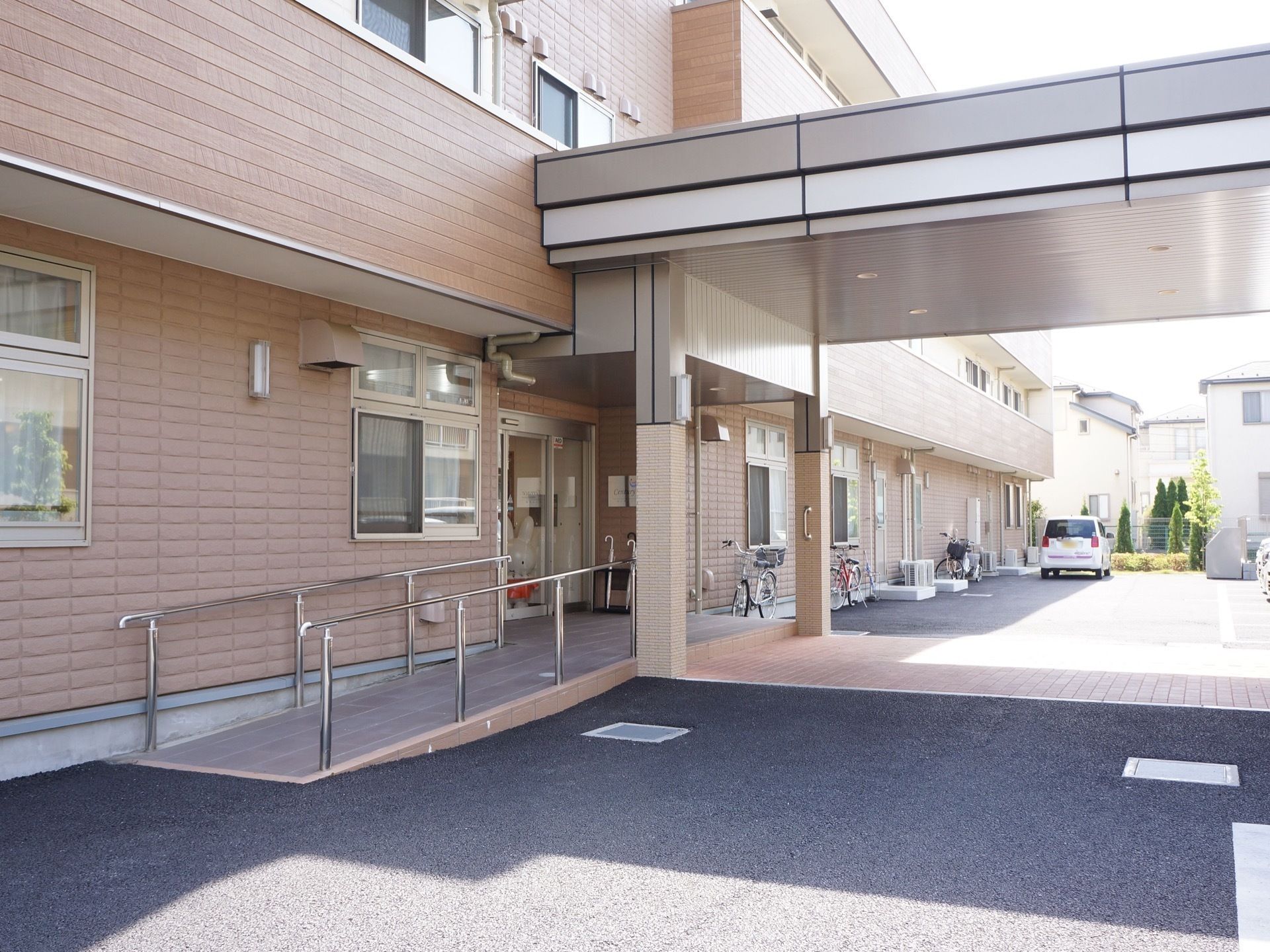 外玄関は、自動ドアまで車椅子でも出入りがしやすい緩やかなスロープが設置されている。雨の日も濡れないような大きい屋根が付いている。