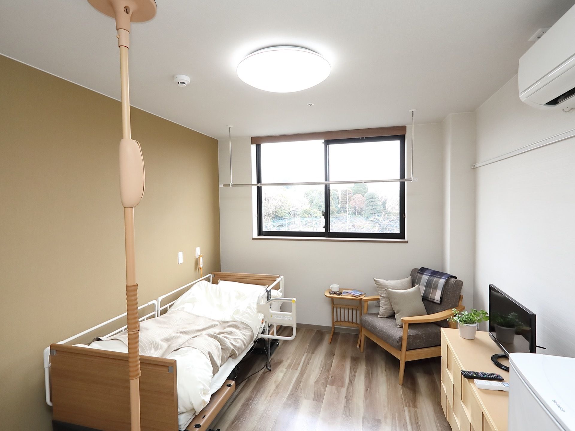 白と木目を基調とし、落ち着いた印象に整えられている居室には、窓際に吊るし型の物干しバーが設置されている。