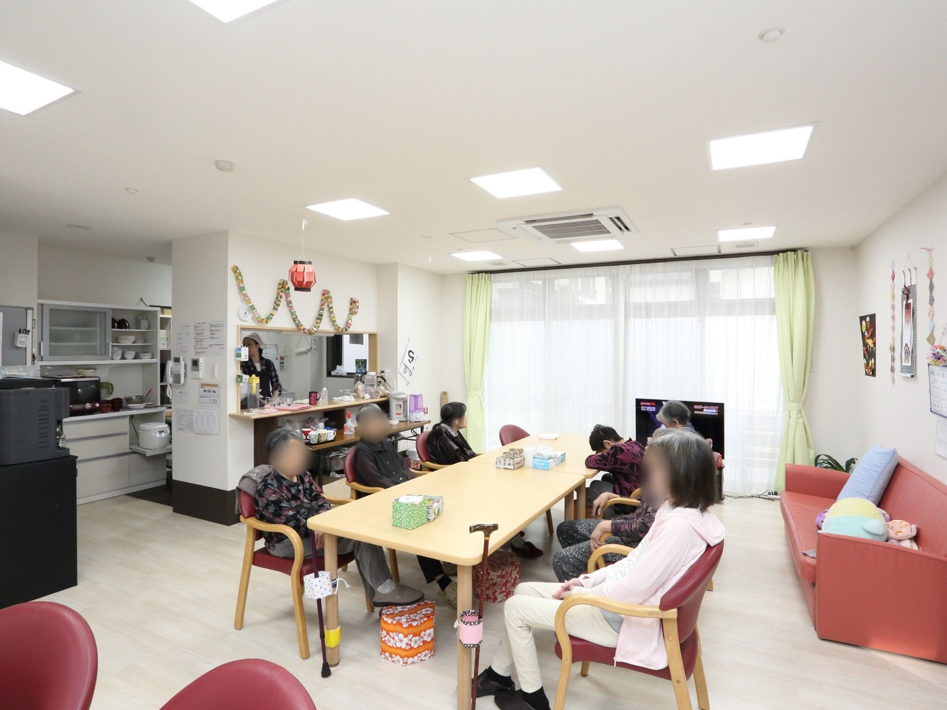 テーブル、椅子、ソファーがある。テレビがあり、ゆっくりくつろげる空間である。壁、天井が白く清潔感がある。