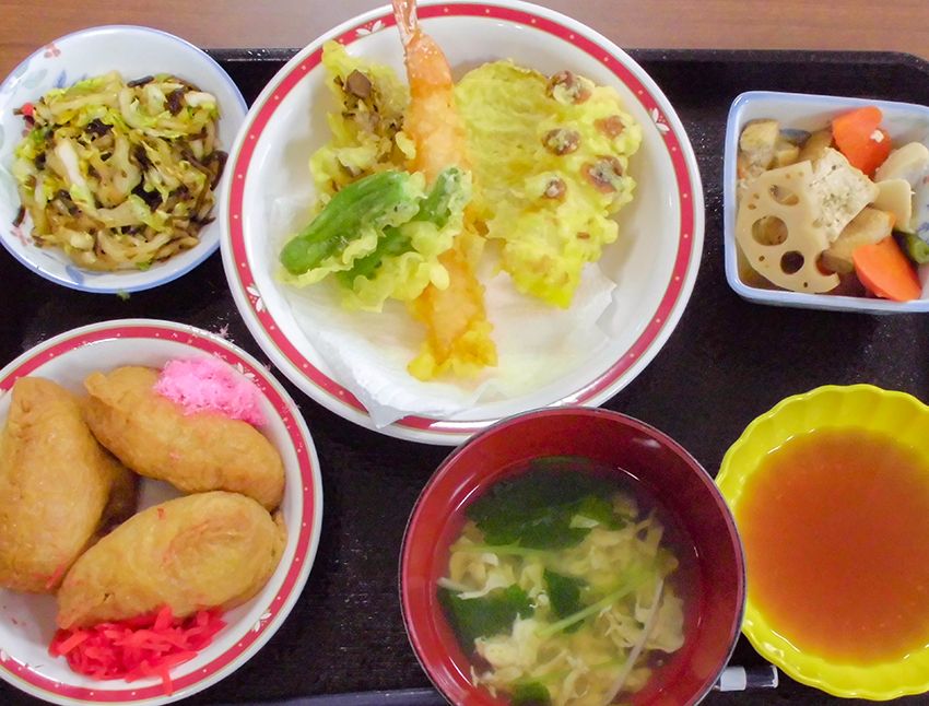天ぷらといなり寿司と野菜の煮物や炒め物がセットになった和食