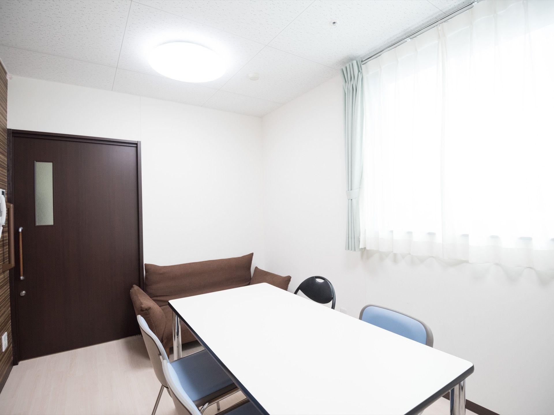 白を基調とした個室の談話室である。白い長方形のテーブルや椅子がある。また、茶色のソファも壁際に置かれている。