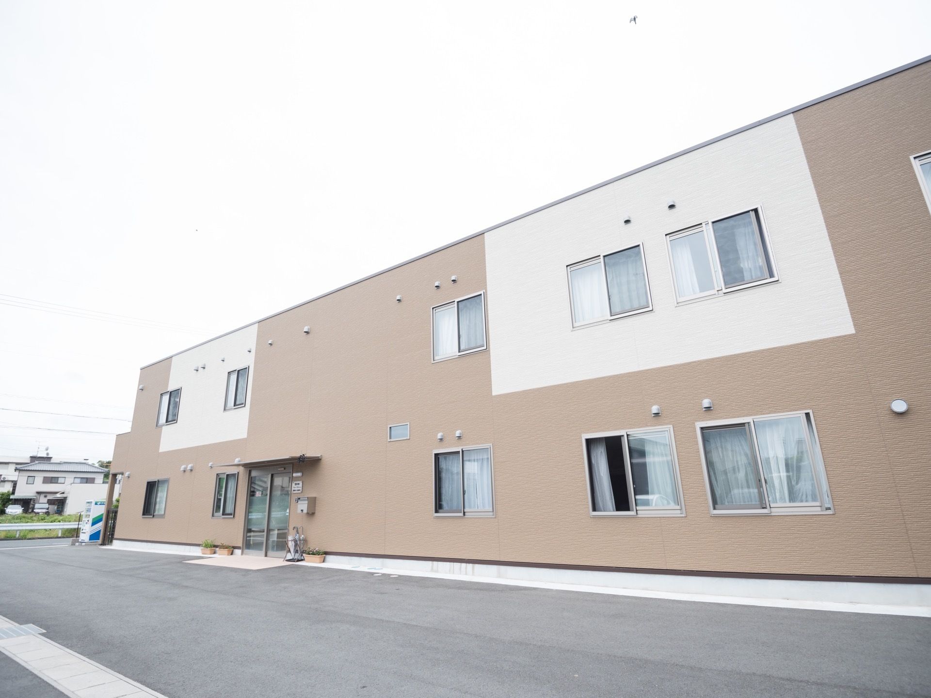 白と茶色で構成された、２階建ての四角い建物である。１、２階共に、窓と換気口が複数並んでいる。玄関前には傘立てが置かれ、傘も数本ある。