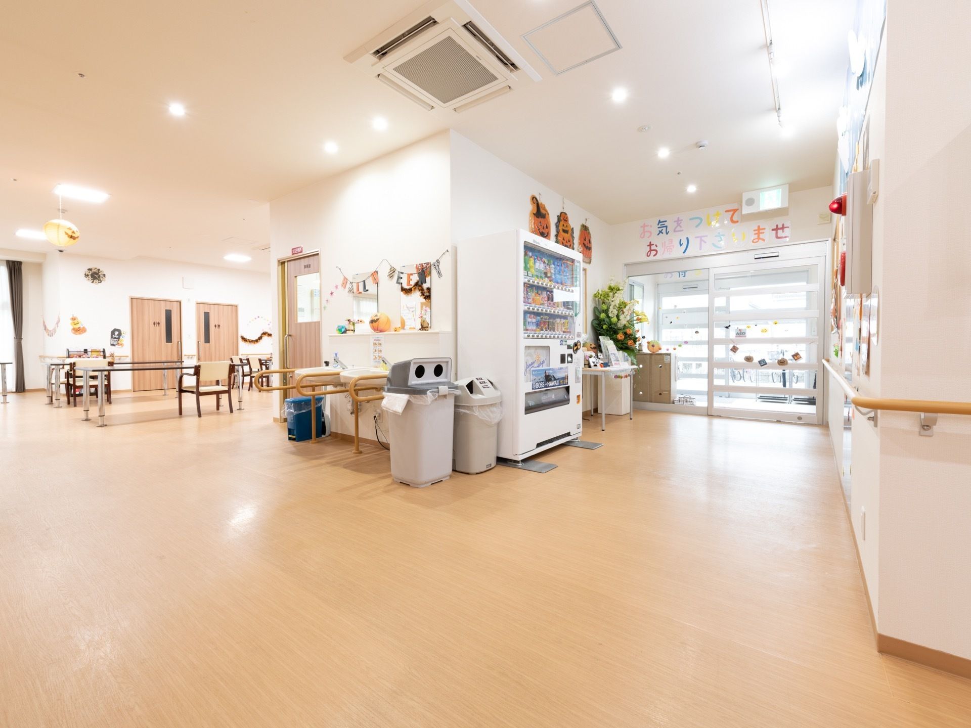 玄関前の廊下は広々としており、自動販売機やゴミ箱が置かれている。入口の自動ドアは、ガラス張りになっている。