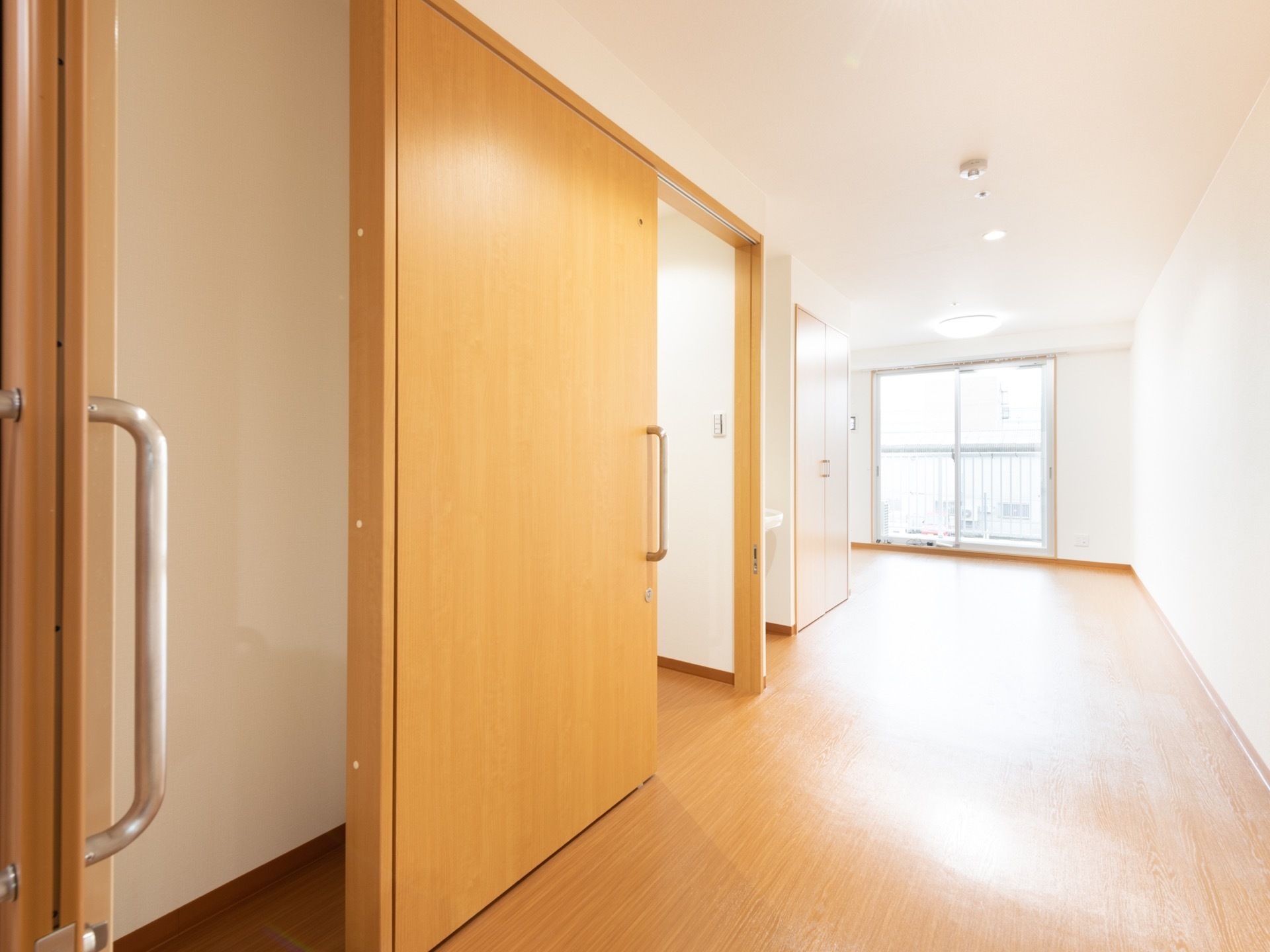 居室は広々としており、入口やトイレの扉には大きな引き戸が取りつけられている。奥には、ベランダも設けられている。