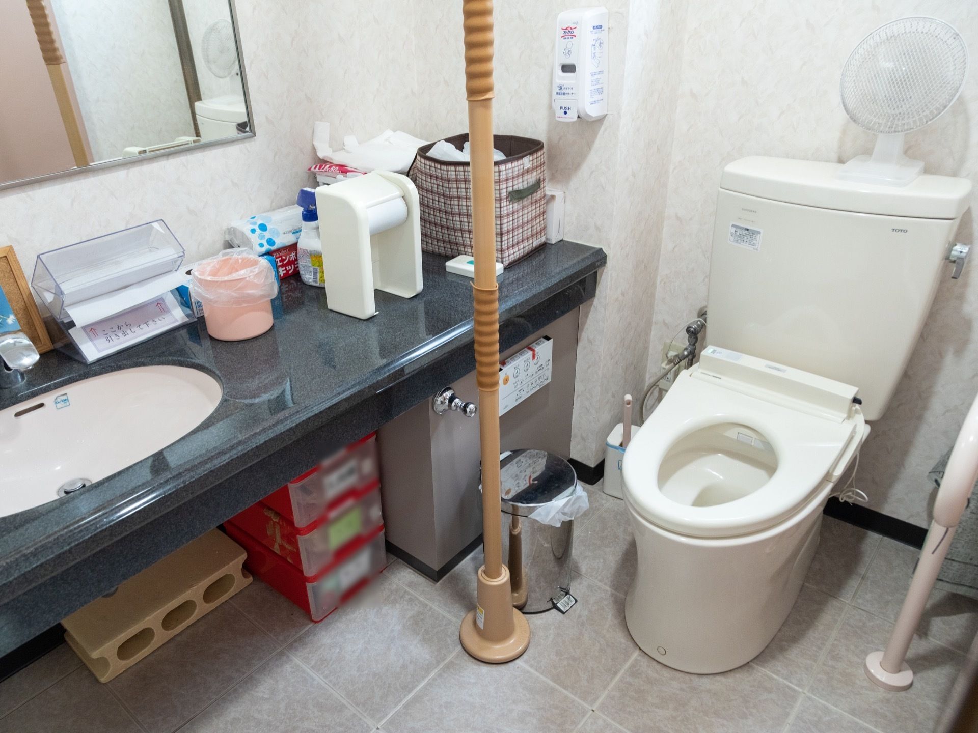 共用設備として用意してある個室トイレ。左手側の手すりに加え、右手側にも天井と床を突っ張るつっかえ棒タイプが追加されている。