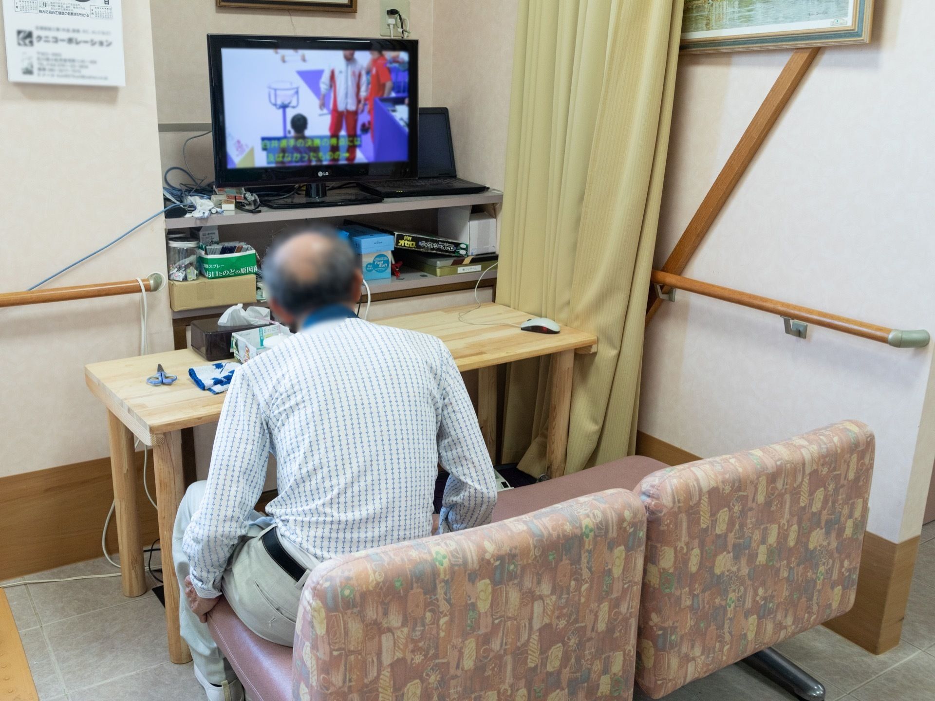 共有スペースには、テレビ用にソファタイプの座席が用意されている。机の下には足裏用の健康器具が設置されている。