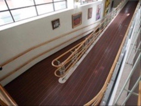 両脇に手すりが取り付けられた、広いスロープ。壁には絵画を飾っているので、目で楽しみながら施設内を散歩することができる。