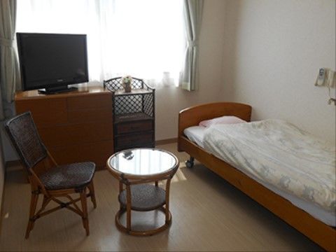 個室タイプの居室である。室内にはベッドやテレビ、洋服ダンスが置かれている。壁にはナースコールが設置されている。