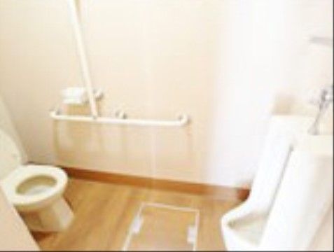白を基調とした清潔感のある広々としたトイレである。温水洗浄便座や男性用の便器、手すりが完備されている。