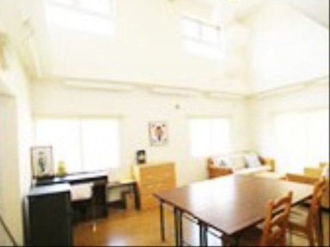 フローリングの床に白い壁が広がっている、天井の高いリビング。窓が複数あり、天気の良い日には日差しが入ってくる明るい空間である。
