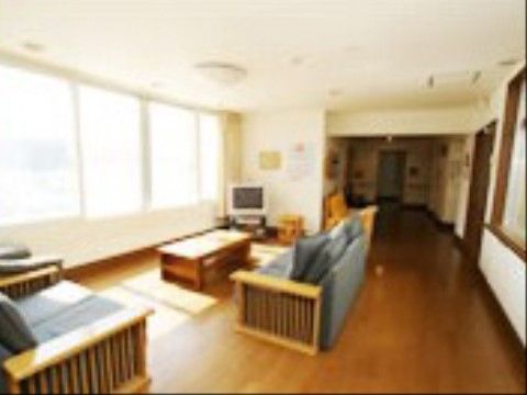 壁と複数の窓とに挟まれたオープンスペースを活用して、テーブル、ソファー、テレビなどゆっくりくつろげる家具を設置している。