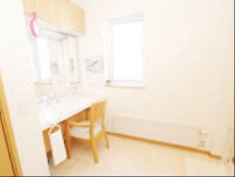 洗面台の側には窓があり、自然光を活用してお化粧ができる。鏡の前には椅子を置いている。収納棚が付いている。