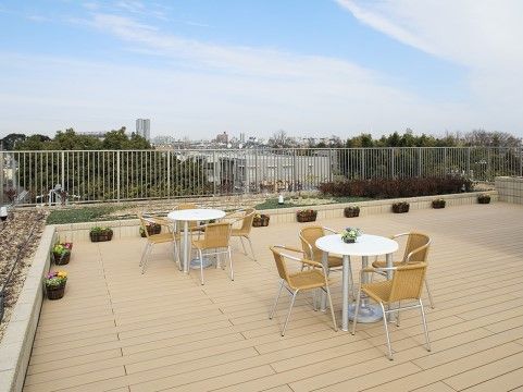 屋上には広いスペースがあり、建物周囲の緑豊かな景色を眺めることができる。丸いテーブルと手すり付きの椅子が２セット置かれている。