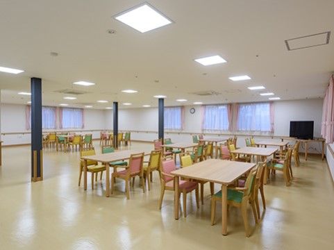 ピンク、緑、黄色のカラフルな椅子が特徴的な明るい食堂